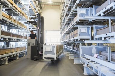 worker with forklift in factory warehouse